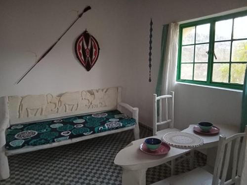 a room with a bed and a table and a window at Tango house in Ukunda