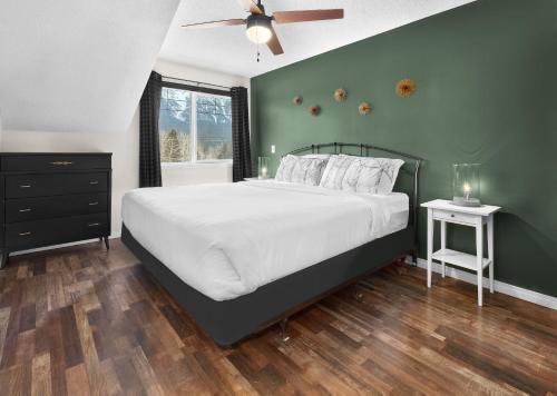 a bedroom with a large bed with a green wall at Mountain Gate - Pet Friendly 2BR w Mountain Views and open hot tub in Canmore