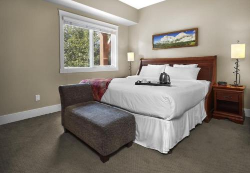 Un dormitorio con una cama grande y una silla. en Star Suite -Luxurious condo with 3 fireplaces, and open Pool!, en Canmore