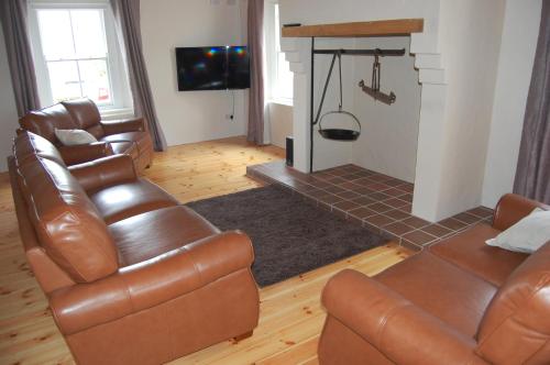 a living room with leather furniture and a fireplace at The Castle Bed & Breakfast in Ballintoy