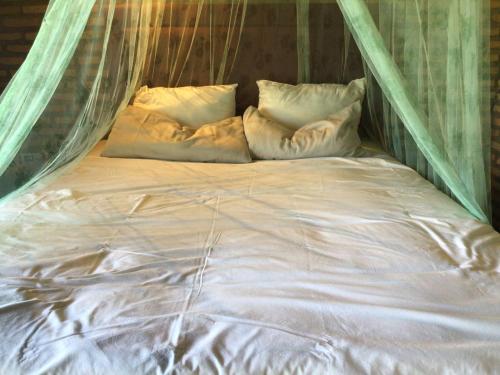 białe łóżko z poduszkami i moskitierą w obiekcie Tranquilo Lodge & Camping w mieście La Colmena