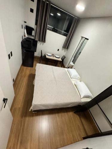 a bedroom with a bed and a desk in it at 3Kitnet nova ao lado de tudo que você precisa in Lavras