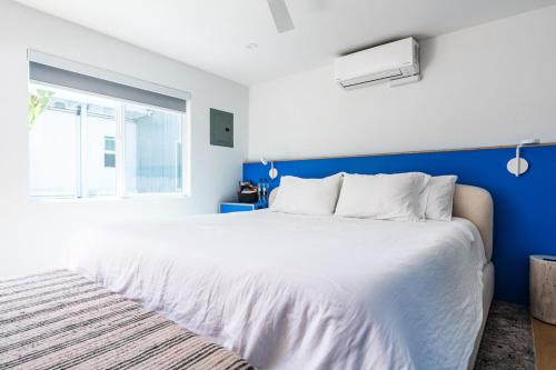a bedroom with a large white bed and a blue wall at Simple La Jolla Epic bungalow #7 in San Diego