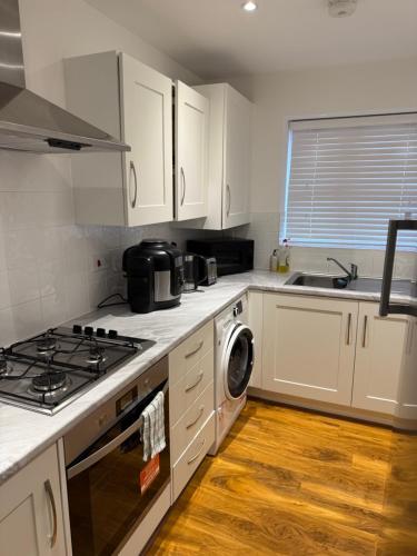 a kitchen with white cabinets and a stove top oven at Large Double Room in Longbridge