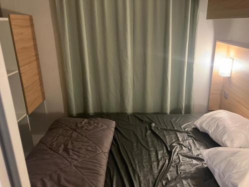 a bed in a bedroom with a green curtain at Mobil home 6 personne in La Tranche-sur-Mer