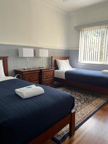 a bedroom with two beds and a desk and a window at Beryls House in Coffs Harbour