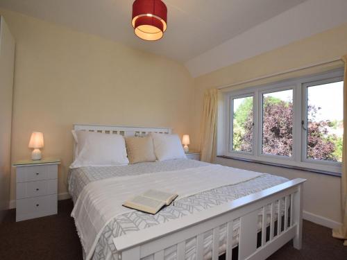 a bedroom with a large bed with two windows at 1 Bed in Kilve KILVE in Kilve