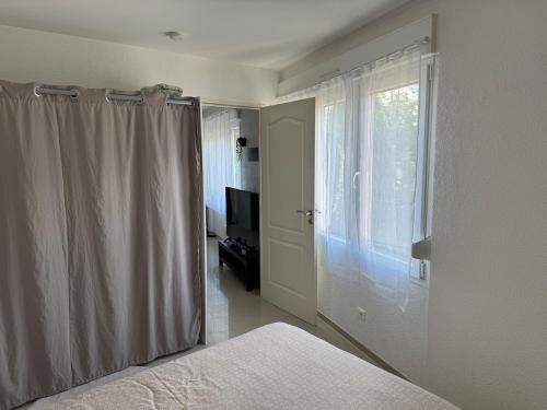 een slaapkamer met een bed en een raam met een gordijn bij EJolie in Illzach