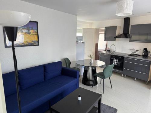 ein Wohnzimmer mit einer blauen Couch und eine Küche in der Unterkunft EJolie in Illzach