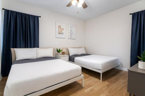 two beds in a room with blue curtains at Luxurious 3-Bedroom House w Priv Pool Game Room in Delray Beach