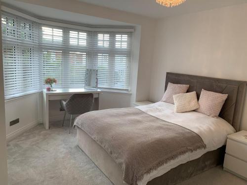 a bedroom with a bed with a desk and windows at Birkdale Open - modern 3 bedroom family home in Ainsdale