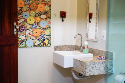 a bathroom with a sink and a painting on the wall at Barra Quintal Studio 3 in Barra Grande
