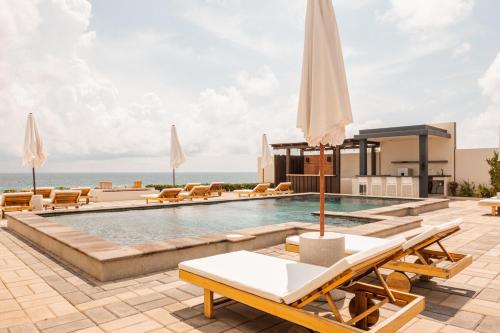 una piscina en un resort con sillas y sombrillas en The Garden Suite, en El Rebalse