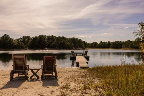 two chairs and a dock on a lake with a boat at Private Lake and Hiking, The Loft at Haven in Cape May Court House