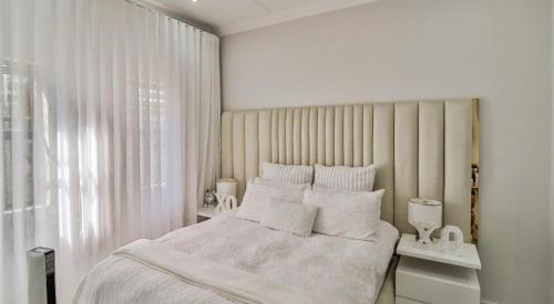 a white bedroom with a large bed and a window at LiFa Luxury Sandton Retreat in Johannesburg