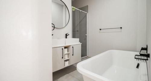 a white bathroom with a tub and a sink and a mirror at LiFa Luxury Sandton Retreat in Johannesburg