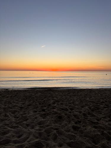 a beach with the sun setting over the ocean at Appartement costa mar Martil in Martil