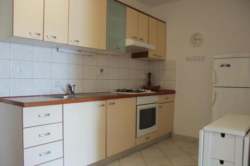 Una cocina con gabinetes blancos, un fregadero y una estufa. en Apartment Leslie, en Mali Iž