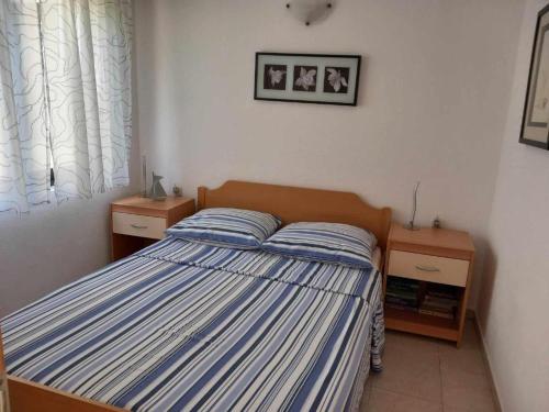Un dormitorio con una cama con rayas azules y blancas. en Apartment Leslie, en Mali Iž