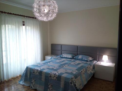 a bedroom with a bed with a blue blanket and a chandelier at Blue Ocean in Póvoa de Varzim