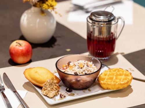 a plate of food with a bowl of cereal and an apple at Novotel Paris 13 Porte d'Italie in Le Kremlin-Bicêtre