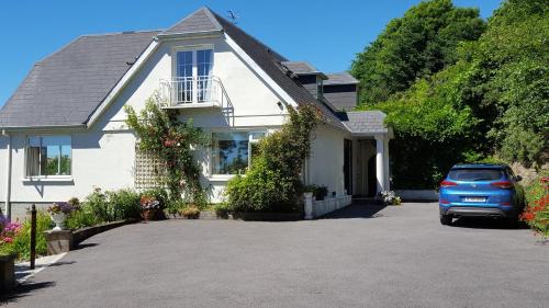 a white house with a car parked in the driveway at Rocklands House Bed and Breakfast in Kinsale