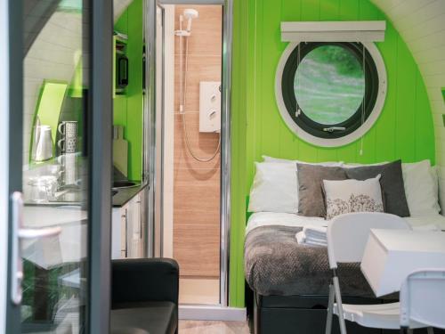 a green room with a bed and a round window at 1 Bed in New Quay 78189 in Lampeter