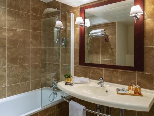 a bathroom with a sink and a tub and a mirror at Mercure Rambouillet Relays Du Château in Rambouillet