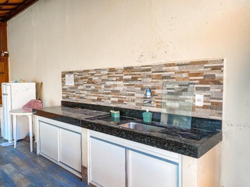 a kitchen with a sink and a brick wall at Flat com 1 quarto com ar split, sala e cozinha completa, No condomínio Portal do Atlântico a 100m praia de Taperapuã (Barraca do Gaúcho) , portaria 24hrs, piscina. in Coroa Vermelha
