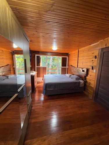 Dos camas en una habitación con paredes de madera. en Casa da Árvore, en Foz do Iguaçu