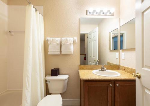 a bathroom with a toilet and a sink and a mirror at Villas at Regal Palms Resort & Spa in Davenport