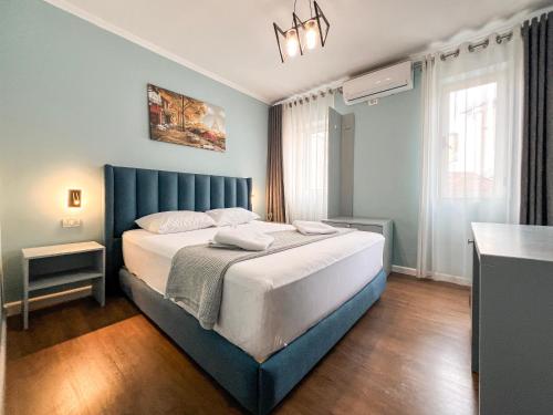 une chambre avec un grand lit avec une tête de lit bleue dans l'établissement Tier Hotel, à Tirana