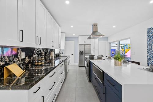 a kitchen with white cabinets and black counter tops at Spacious 4BR Waterfront Home with Private Pool, Tiki Hut & Free Parking near Miami & Key Largo in Cutler Bay