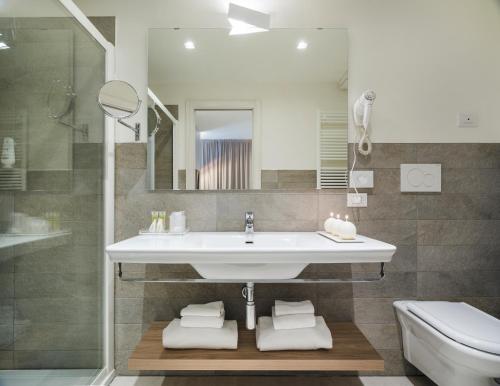 a bathroom with a sink and a toilet and a mirror at Hatelier Garda Home by Enjoy Garda Hotel in Peschiera del Garda