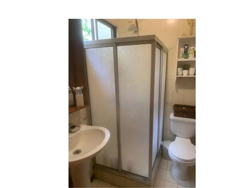 a white bathroom with a toilet and a sink at Hostal Edificio Kuramochi in Temuco