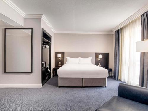 a bedroom with a white bed and a mirror at Sofitel London Gatwick in Horley