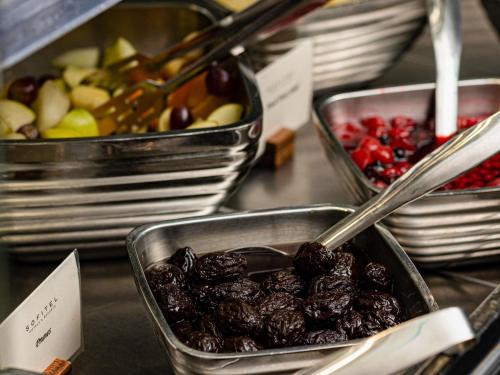 ホーリーにあるソフィテル ロンドン ガトウィックのフルーツが添えられた食べ物のトレーが並んだビュッフェ