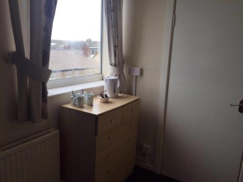 a room with a window and a wooden dresser with a dresser at MyRoomz New Discovery Hotel in Blackpool