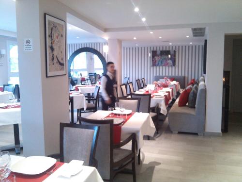 a person standing in a restaurant with tables and chairs at Al Mandari Hôtel Tétouan in Tetouan