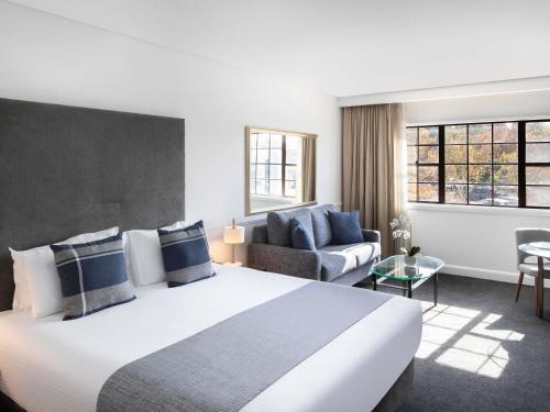 a hotel room with a large bed and a couch at Peppers The Hills Lodge in Castle Hill
