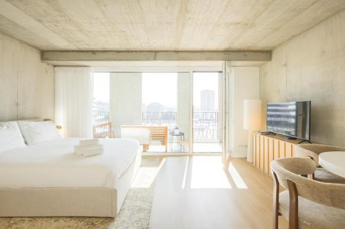 a bedroom with a white bed and a balcony at * Blanc Studio Aveiro * in Aveiro