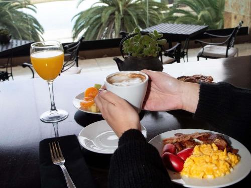a person sitting at a table with a cup of coffee and breakfast at Sofitel La Reserva Cardales in Río Luján