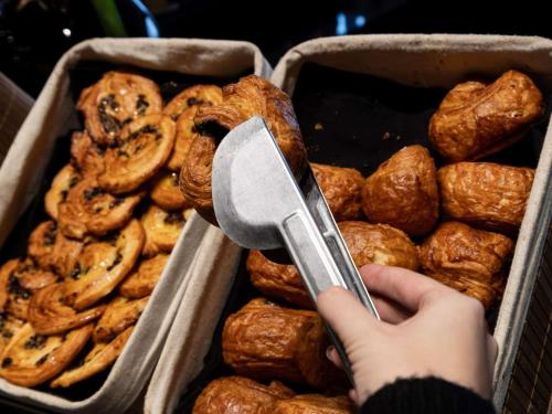a person holding a spatula over a tray of bread at Sofitel La Reserva Cardales in Río Luján