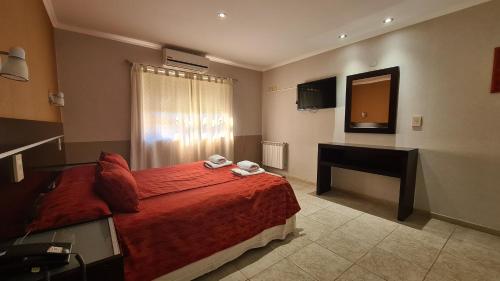 a bedroom with a bed and a desk and a television at El Condor Hotel SPA in Merlo
