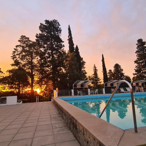 a swimming pool with the sunset in the background at El Condor Hotel SPA in Merlo