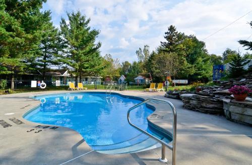 a large swimming pool with a metal rail in a yard at Super 8 by Wyndham Gananoque - Country Squire Resort in Gananoque