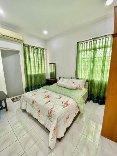 a bedroom with two beds and green curtains at Homestay Harmony in Melaka
