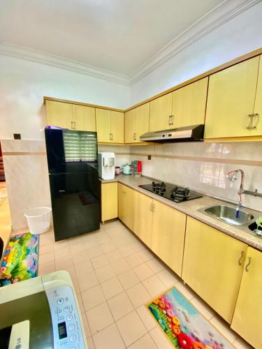 a kitchen with yellow cabinets and a black refrigerator at Homestay Harmony in Melaka