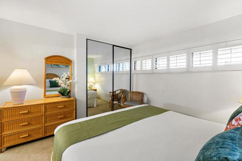Un dormitorio con una cama, una cómoda y un espejo. en Sugar Beach 304, en Kihei