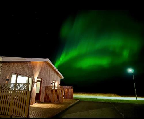 a house with the green northern lights in the sky at Lónið Apartments in Höfn